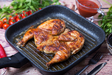 Fried chicken tobacco (tabaka) in a grill pan. Selective focus, close-up.