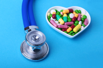 Stethoscope, RX prescription and colorful assortment pills and capsules on plate.