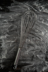 whisk on black table with flour