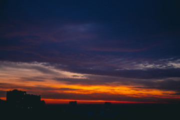 Cityscape with wonderful varicolored fiery dawn. Amazing dramatic multicolored cloudy sky. Dark...