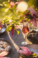 Beautiful table setting in garden on sunset light. Table decorated with magnolia flowers under magnolia tree.
