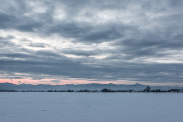 landscape of carpathian mountains covered with snow with cloudy sky and trees at dawn
