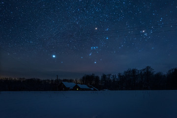 starry dark sky and house in carpathian mountains at night in winter