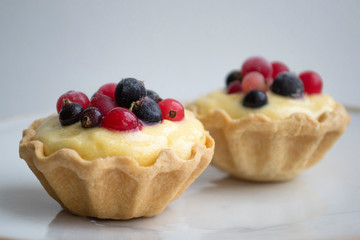 Delicious dessert, tartlets, baskets with sabaione sabaglione cream decorated with berries on white background