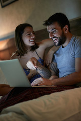 couple having fun relaxing on bed at home in night time enjoying.