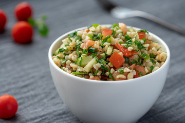Oriental salad tabbouleh from bulgur, parsley and tomatoes in a white  bowl.