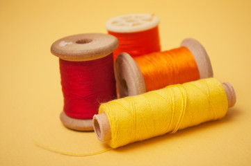 closeup of sewing thread spool bobbins on yellow background