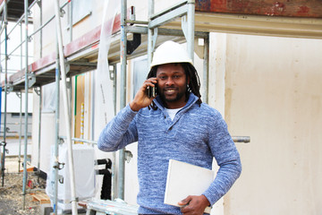 A happy man making a call and communicating on site, giving update of the progress on site