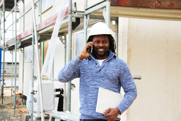A happy man making a call and communicating on site, giving update