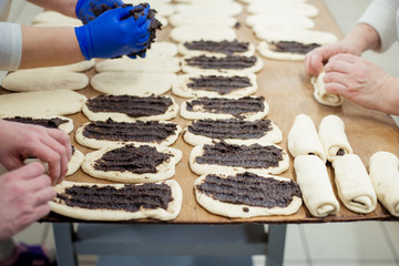 Bakers make buns from dough with poppy filling