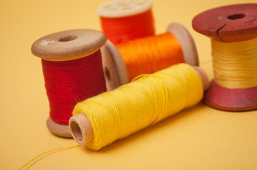 closeup of sewing thread spool bobbins on yellow background
