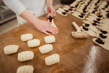 Fototapeta na wymiar Woman baker make buns with fruit filling from dough