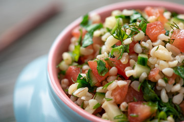 Oriental salad tabbouleh of bulgur, parsley and tomatoes in a blue pot.