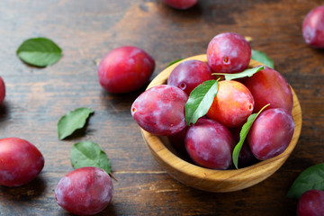 Fototapeta na wymiar Wooden plate with ripe juicy plums on table.