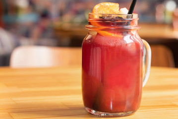 Close up glass jar with hot mulled wine and straw on light wooden table