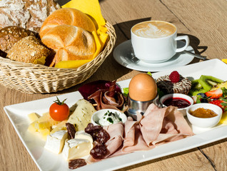 Frühstücksteller mit Brötchen und Cappuccino
