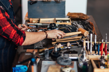 master putting tools on the table. side view cropped photo, goldsmith has finished his work