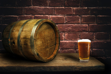 Wooden barrel and glass of beer on a old oak table of wood.
