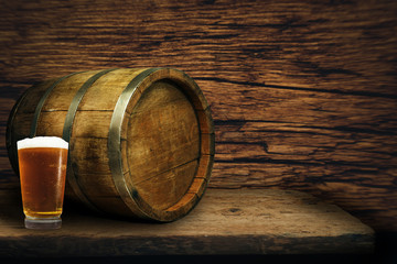 Wooden barrel and glass of beer on a old oak table of wood.