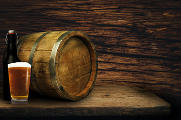 Wooden barrel and glass of beer on a old oak table of wood.