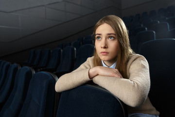 Beautiful emotional woman watching drama movie at the cinema