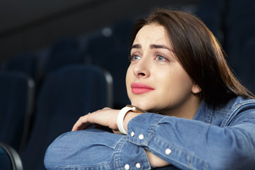 Beautiful emotional woman watching drama movie at the cinema