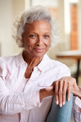 Fototapeta na wymiar Portrait Of Smiling Senior Woman Relaxing On Sofa At Home