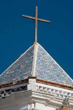 Metal cross on the octagonal roof of the chapel of the Hermitage of Santo Christo - old center of Marbella, Spain. This roof is covered by small coloured azulejos.