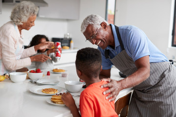 Grandparents In Kitchen With Grandchildren Making Pancakes Together