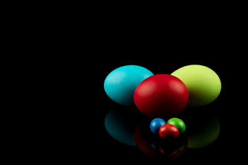 Easter Eggs. Red Green Blue Easter Eggs on black background with reflection. Modern Design. Copy Space