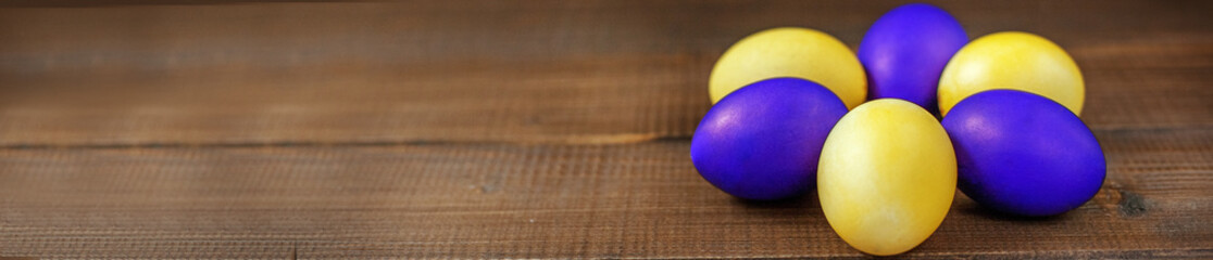 Yellow and purple Easter eggs on a wooden table. The concept of