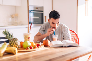 Fototapeta na wymiar healthy strong young man reading a book early in the morning while making his smoothie.