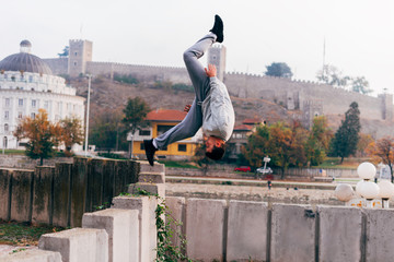 Free runner training parkour jumping on a fence while doing a back flip in the air.