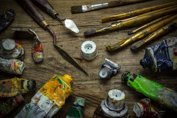 Old paint tubes and brushes on wooden background 