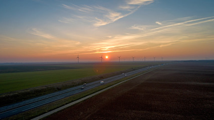 Fototapeta premium Wind turbines along the highway at sunset, France