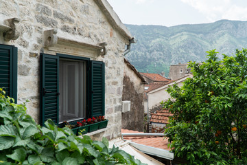 The window in the old Stone House with wooden shutters is wide open to the new Day with a mountain in the background in the European city