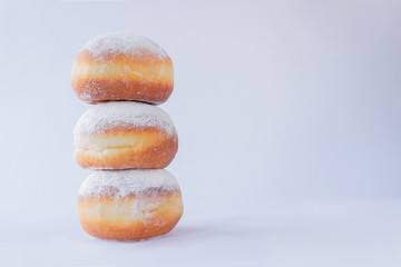 Three fresh doughnuts stacked on each other on white background