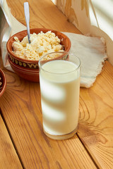 Baked pies with cottage cheese and a glass of milk, on the morning table, in the bright rays of the sun.