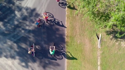 Overhead view of family of five cycling together in peaceful neighborhood.