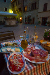 White wine and tasty italian homemade snack. Italian dinner table with homemade antipasti, cheese and ham, Pienza, Tuscany, Italy