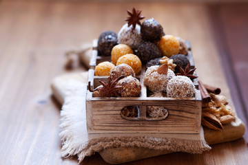 Vegan organic energy bites with nuts, chia, dates, coconut and dried fruits, healthy raw dessert snacks on wooden table