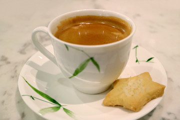 Cup of hot coffee with star shaped butter cookie served on white table