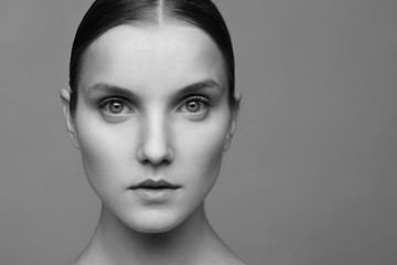 Close-up portrait of a beautiful model with clean makeup and collected hair, photographed in a photo studio