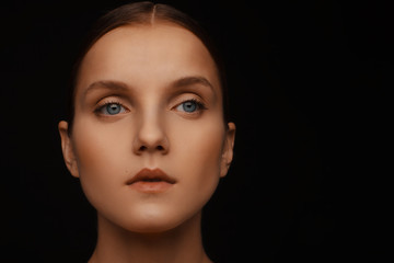 Close-up portrait of a beautiful model with clean makeup and collected hair, photographed in a photo studio