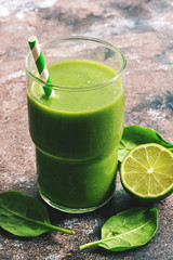Close - up of green vegan smoothie with spinach in a glass of straw. Selective focus.