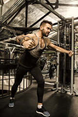 Fototapeta na wymiar Handsome young muscular athlete doing chest workout on cable crossover machine
