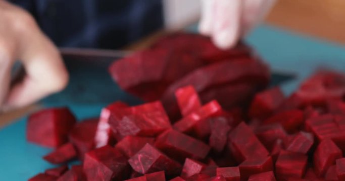 Cooking at home, Man chopping beetroot using sharp knife, close-up, steadicam