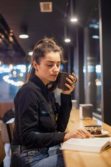 young attractive brunette is having fun at the cafe, smiling and posing for the photo in the evening. selective focus, noise effect