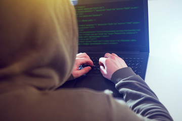 Hackers programmer look on screen and writes the program code hack information and user account