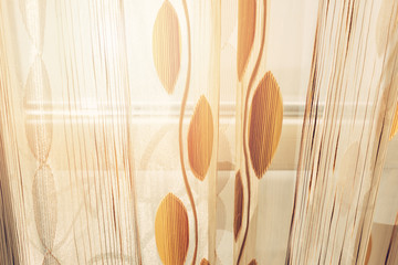 Window of a balcony with transparent curtains and view of morning sun and sea